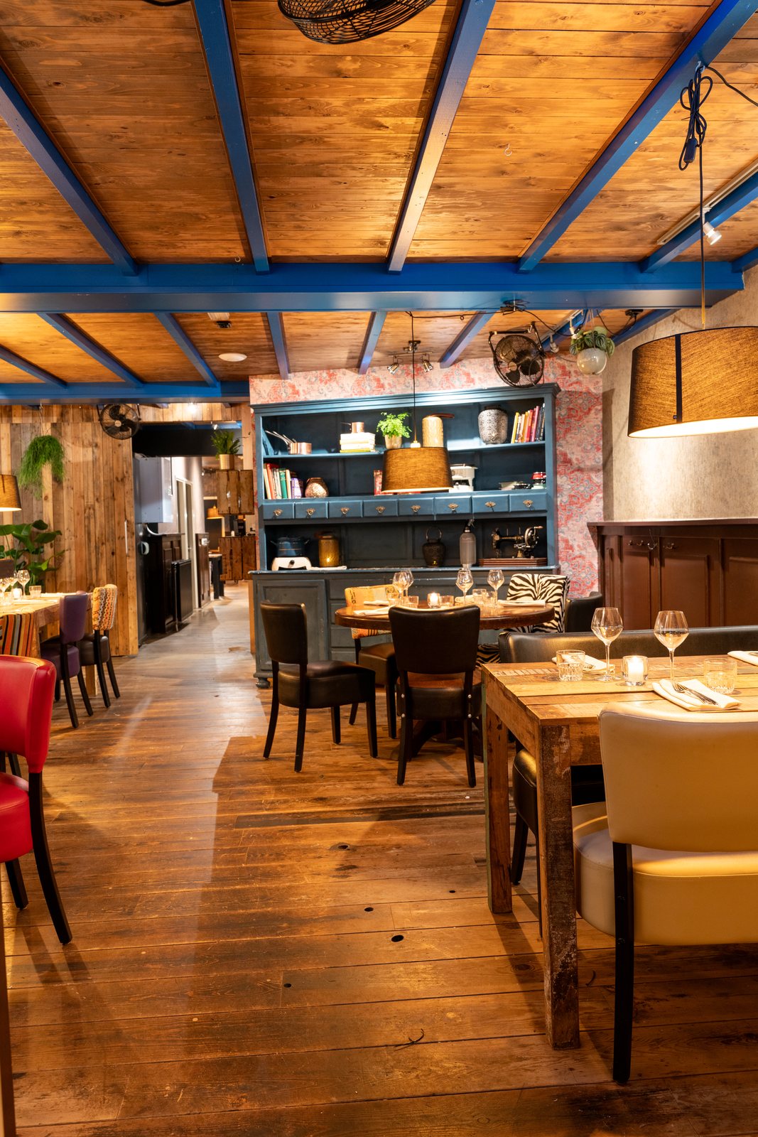 Overzicht van de Bijkeuken bij DOKs Dining met gedekte tafels onder de blauwe balken van het plafond
