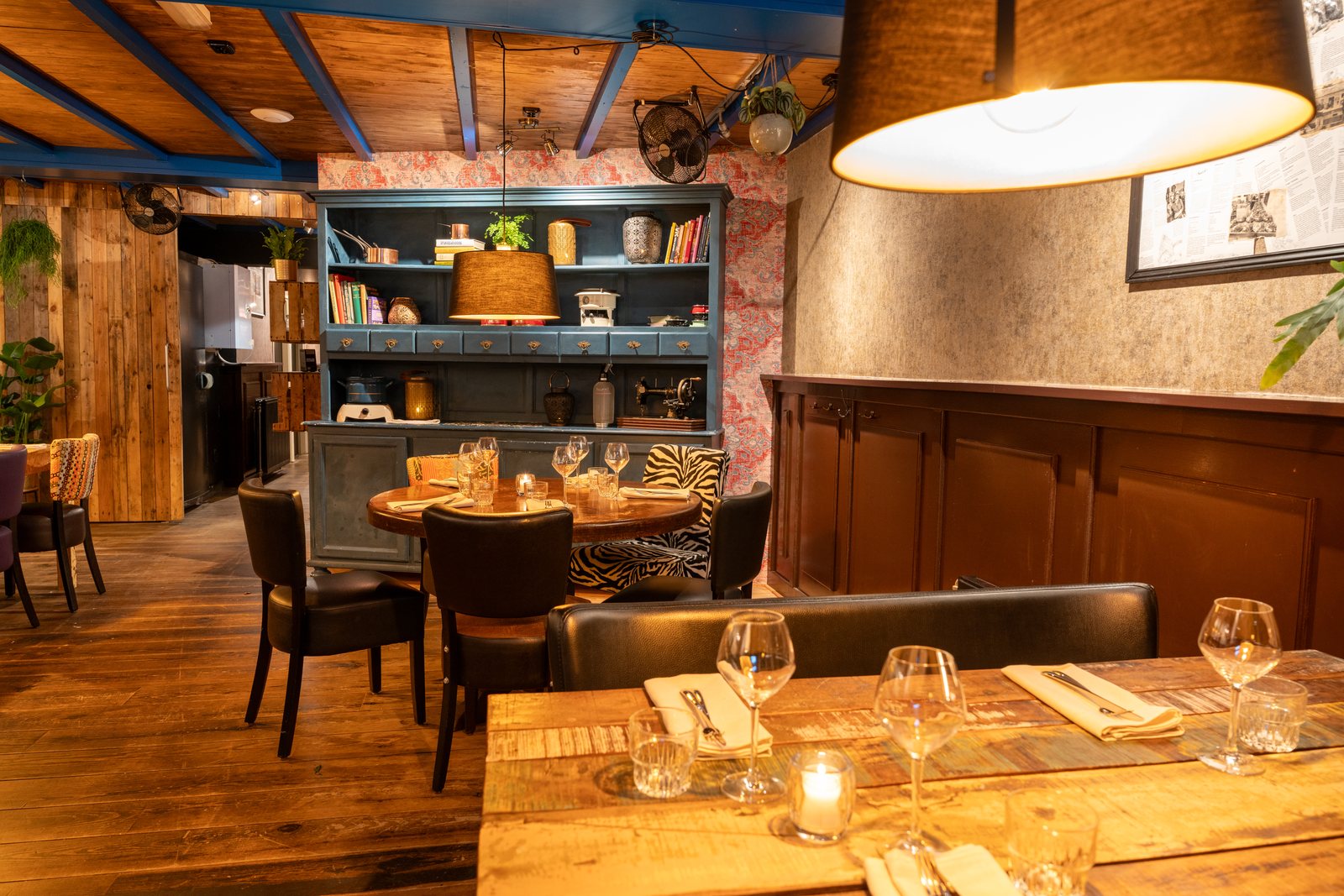 Hoek van de Bijkeuken bij DOKs Dining met een open kast, warme lampen en een gedekte tafel op de voorgrond